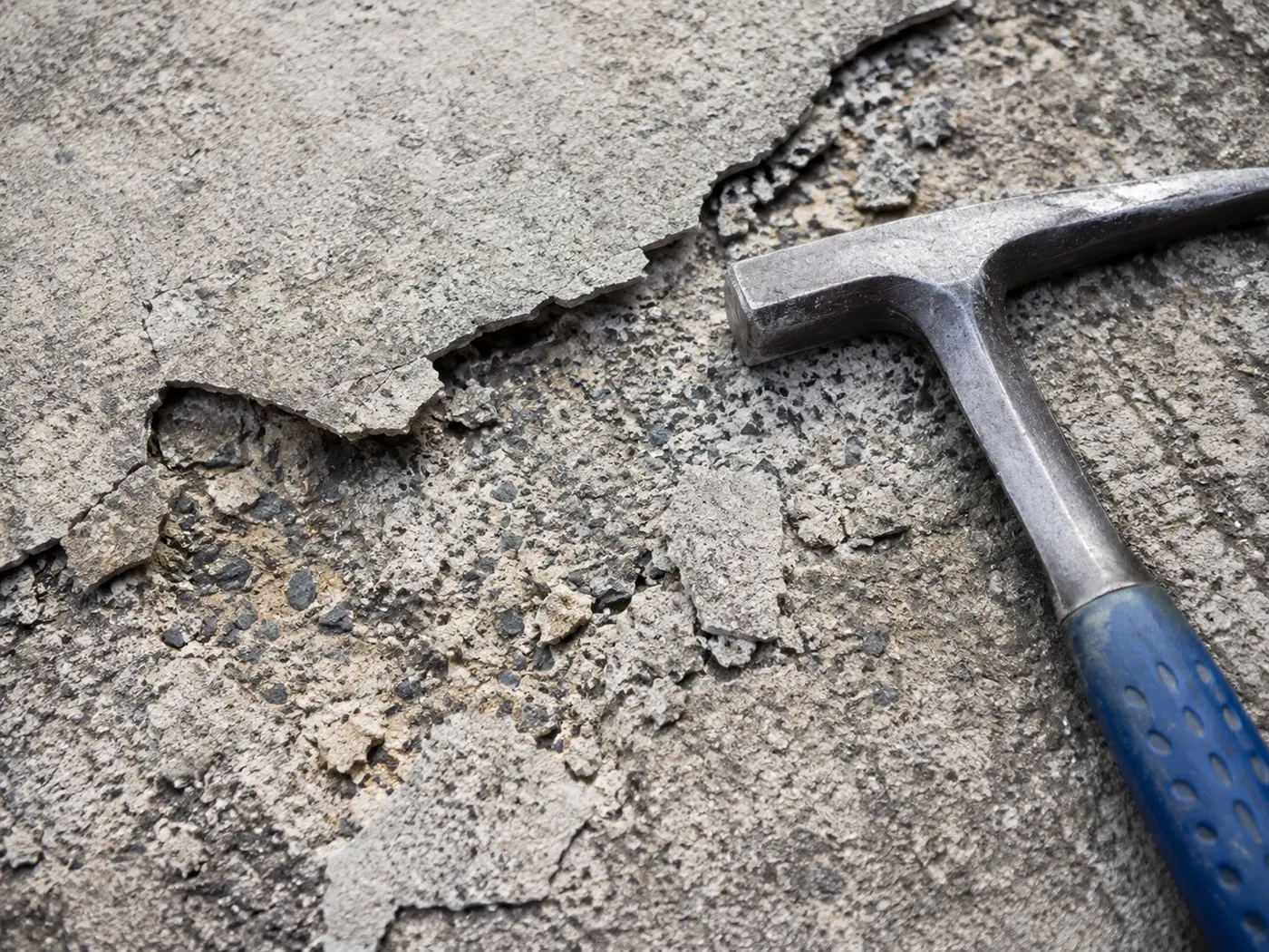 Delaminated concrete flakes lifting from a spalled driveway surface