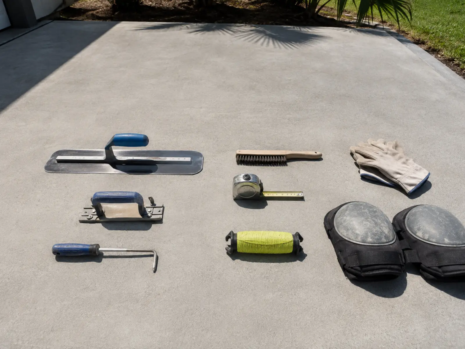 Trowel, edger, groover, brush and string line. Most of what decides a driveway happens before any of these come out.